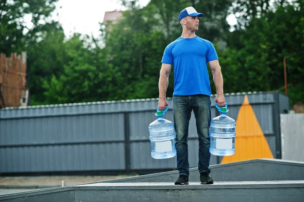 Delivery man with water bottles at hands.