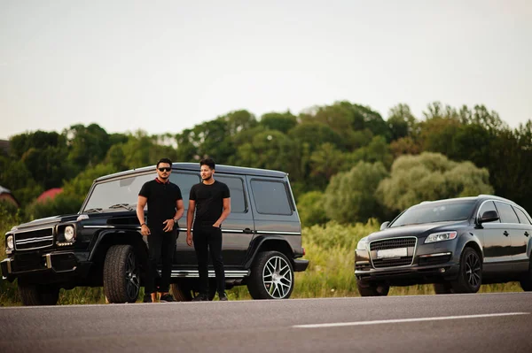 两个亚洲兄弟穿着一身黑色的衣服在越野车附近摆姿势 — 图库照片