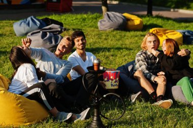 Açık hava sinemasında film izleyen çok ırklı bir grup genç..