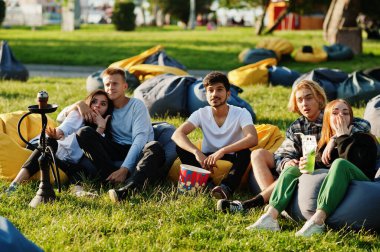 Açık hava sinemasında film izleyen çok ırklı bir grup genç..