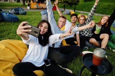 Açık hava sinemasında film izleyen ve telefonda selfie çeken çok ırklı bir grup genç..