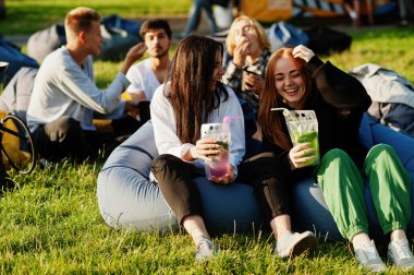 Açık hava sinemasında film izleyen çok ırklı bir grup genç. Mojito kokteyli içen iki kız..
