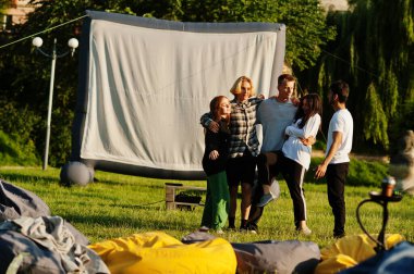 Açık hava sinemasında film izleyen çok ırklı bir grup genç..