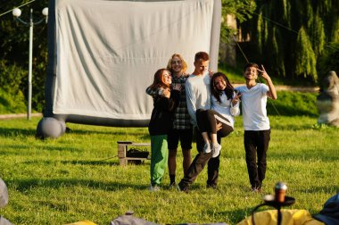 Açık hava sinemasında film izleyen çok ırklı bir grup genç..