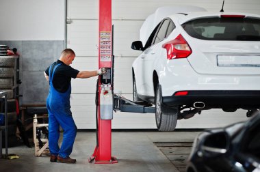 Araba tamiri ve bakım teması. Otomatik serviste çalışan tamirci, Otomatik kaldırmak için düğmeye basın.
