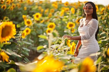 Güzel siyah kadın ayçiçeği tarlasında yaz elbisesi giymiş..