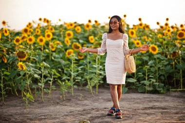 Güzel siyah kadın ayçiçeği tarlasında yaz elbisesi giymiş..