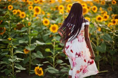 Güzel siyah kadın ayçiçeği tarlasında yaz elbisesi giymiş..