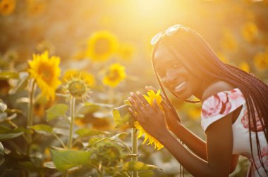 Güzel siyah kadın ayçiçeği tarlasında yaz elbisesi giymiş..