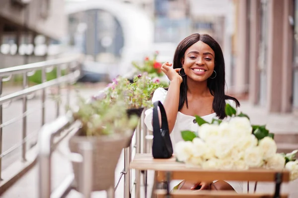 在城市里约会时 美丽的非洲裔美国女孩手持一束白玫瑰花 外面的咖啡店里 坐在桌旁的是一束花的黑人女商人 — 图库照片