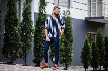 Başarılı bir Arap erkeği çizgili gömlek ve güneş gözlüğü takıyor..