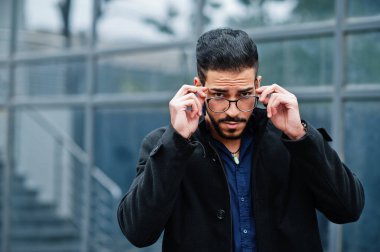 Orta Doğulu girişimci, ofis binasına karşı siyah ceket ve mavi gömlek giyiyor..