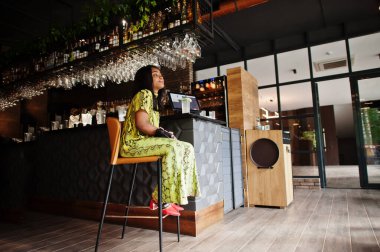 Çekici Afrikalı Amerikalı kadın şık bir yılan elbisesi ve güneş gözlüğü takıyor..