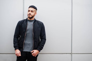 Tarz sahibi Arap sakallı adamın portresi gri balıkçı yaka ve siyah jaket giyiyor. Çelik duvara karşı Arap model adam..