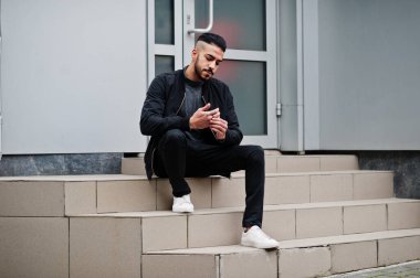 Tarz sahibi Arap sakallı adamın portresi gri balıkçı yaka ve siyah jaket giyiyor. Arap model adam..