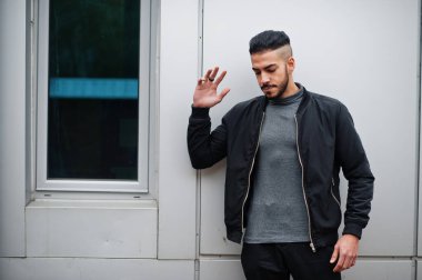 Tarz sahibi Arap sakallı adamın portresi gri balıkçı yaka ve siyah jaket giyiyor. Çelik duvara karşı Arap model adam..