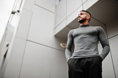 Tarz sahibi Arap sakallı adamın portresi gri balıkçı yaka giyiyor. Çelik duvara karşı Arap model adam..