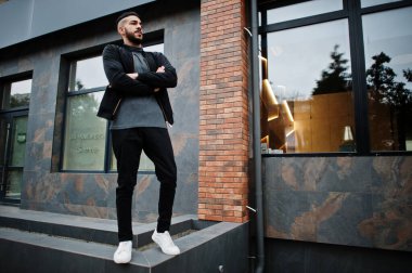 Tarz sahibi Arap sakallı adamın portresi gri balıkçı yaka ve siyah jaket giyiyor. Arap model adam..