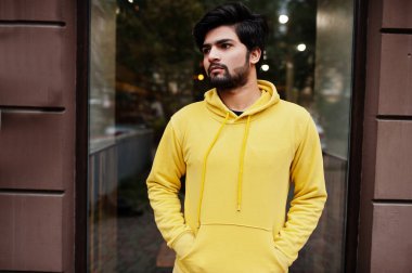 Şık, sarı bir kazak giyen şehirli hippi bir Hintli. Havalı Güney Asyalı adam kapüşonlu giyiyor..