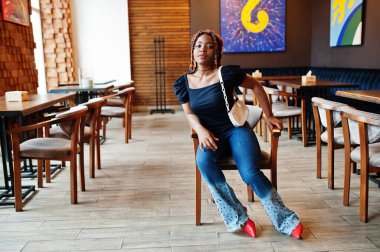 Cafe 'de mavi kotlu rastalı güzel Afrikalı Amerikalı kadın. Güzel, havalı, modaya uygun, siyah, genç bir kız..