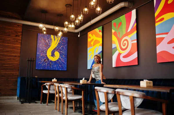 Lovely african american woman with dreadlocks in leopard outfit at cafe. Beautiful cool fashionable black young girl indoor.