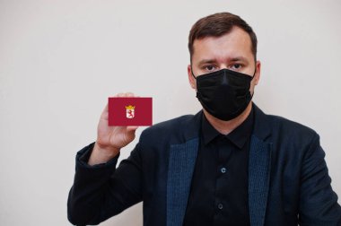 İspanyol adam siyah giyiniyor ve yüz maskesini koruyor. Leon bayrak kartını beyaz arka planda ayrı tutuyor. İspanya, Coronavirus Covid kavramını ilçe ediyor.