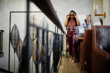 Güzel Afrikalı Amerikalı kadın restoranda kırmızı deri kostüm giymiş..