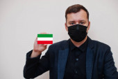 Der deutsche Mann trägt eine schwarze Gesichtsmaske, hält die NRW-Flagge isoliert auf weißem Hintergrund. Deutschland nennt Coronavirus-Covid-Konzept.