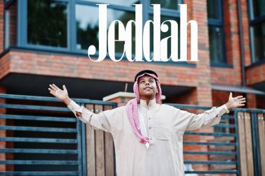 Jeddah - Suudi Arabistan 'ın en büyük şehri. Orta Doğu Suudi Arabistan 'lı adam ellerini havaya kaldırarak modern yapıya karşı caddede poz verdi.