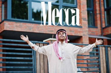 Mekke, Suudi Arabistan 'ın en büyük şehri. Orta Doğu Suudi Arabistan 'lı adam ellerini havaya kaldırarak modern yapıya karşı caddede poz verdi.