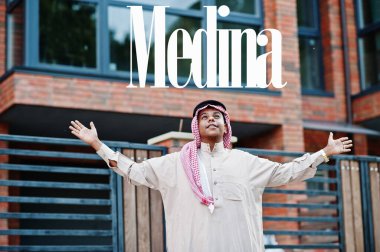 Medine, Suudi Arabistan 'ın en büyük şehri. Orta Doğu Suudi Arabistan 'lı adam ellerini havaya kaldırarak modern yapıya karşı caddede poz verdi.