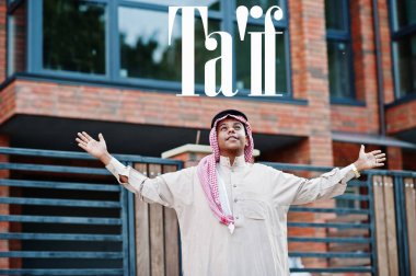 Ta 'if - Suudi Arabistan' ın en büyük şehri. Orta Doğu Suudi Arabistan 'lı adam ellerini havaya kaldırarak modern yapıya karşı caddede poz verdi.