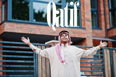 Qatif - Suudi Arabistan 'ın en büyük şehri. Orta Doğu Suudi Arabistan 'lı adam ellerini havaya kaldırarak modern yapıya karşı caddede poz verdi.