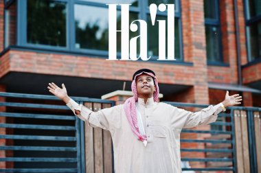 Ha 'il - Suudi Arabistan' ın en büyük şehri. Orta Doğu Suudi Arabistan 'lı adam ellerini havaya kaldırarak modern yapıya karşı caddede poz verdi.