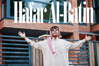 Hafar Al-Batin - Suudi Arabistan 'ın en büyük şehri. Orta Doğu Suudi Arabistan 'lı adam ellerini havaya kaldırarak modern yapıya karşı caddede poz verdi.
