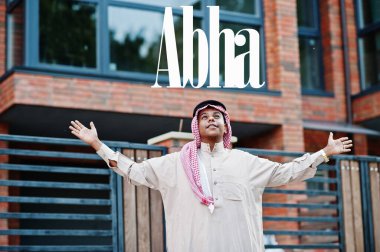 Abha - Suudi Arabistan 'ın en büyük şehri. Orta Doğu Suudi Arabistan 'lı adam ellerini havaya kaldırarak modern yapıya karşı caddede poz verdi.