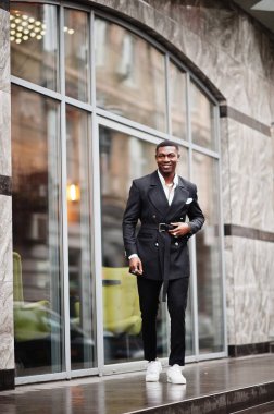 Genç ve yakışıklı Afro-Amerikan iş adamı portresi. Takım elbiseli ve beyaz spor ayakkabılı..