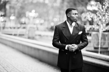 Genç ve yakışıklı Afro-Amerikan iş adamının portresi. Takım elbiseli, şehrin ortasında çelenklerle yürüyor..