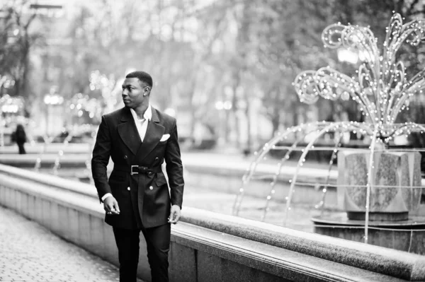 ガーランドと街の中心部を歩くスーツ姿の若くてハンサムなアフリカ系アメリカ人ビジネスマンの肖像 — ストック写真