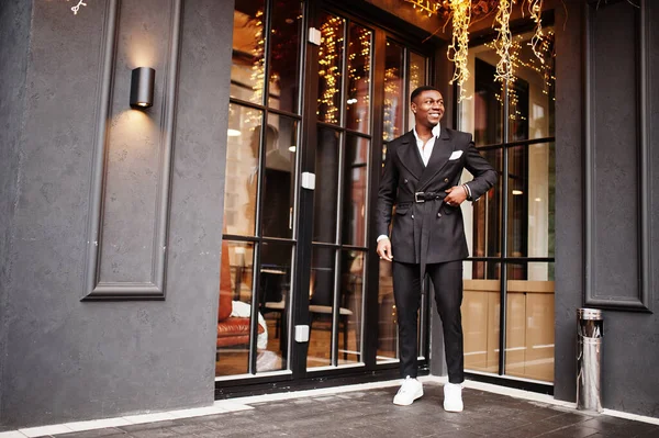 若いとハンサムなアフリカ系アメリカ人ビジネスマンの肖像スーツとガーランドと家に対する白いスニーカー — ストック写真