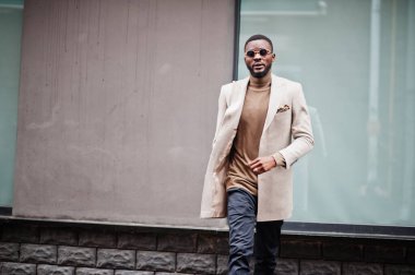 Afro-Amerikalı şık adam güneş gözlüklü bej ceket giyiyor..