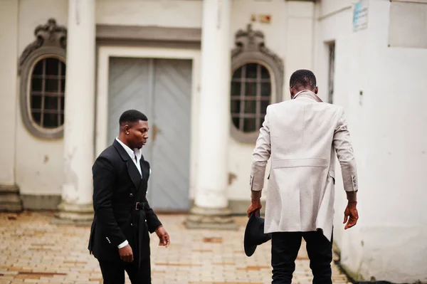 Two fashion black men. Fashionable portrait of african american male models. Wear suit, coat and hat.