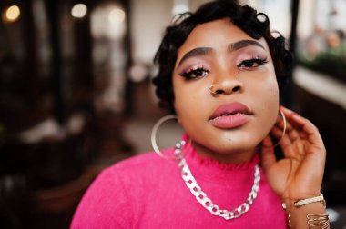 Pembe bluzlu Afro-Amerikan kadın. Burnunda piercing olan afro moda şık kadınlar..
