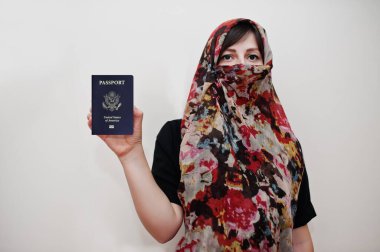 Türbanlı elbiseli genç Arap kadın beyaz duvar arkasında Amerika Birleşik Devletleri (ABD) pasaportu, stüdyo portresi taşıyor. 