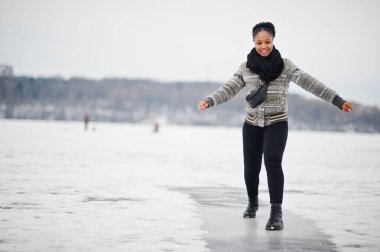 Afrikalı bir kadın donmuş buz gölünde siyah fular takıyor. Avrupa 'da kış günü..