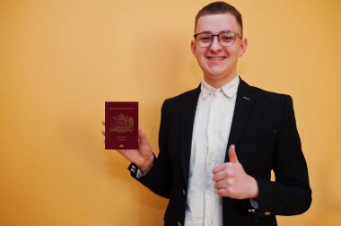 Şili Cumhuriyeti pasaport kimliğini sarı arka planda tutan yakışıklı genç adam, mutlu ve başparmağını kaldırmış. Amerika ülkelerine seyahat.
