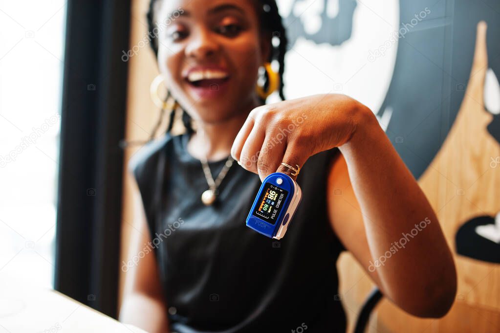 African american women with pulse oximeter on hand measuring oxygen saturation level.