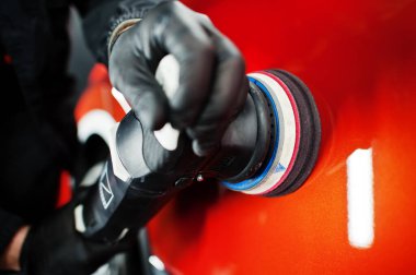 Araba temizleme konsepti. Yörünge cilasıyla turuncu SUV 'u cilalayan bir adamın elleri..