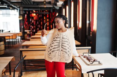 Afrikalı kadın ahşap masada ızgara pirzola yiyor..
