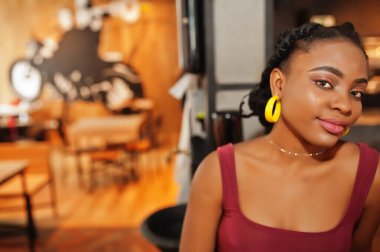 Kırmızı Marsala bluzlu Afrikalı kadın içeride poz verdi..